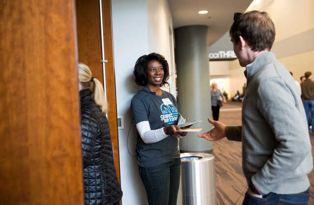 guest services volunteer greeting attendee at the auditorium doors