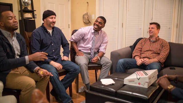 group of men having a conversation in a living room