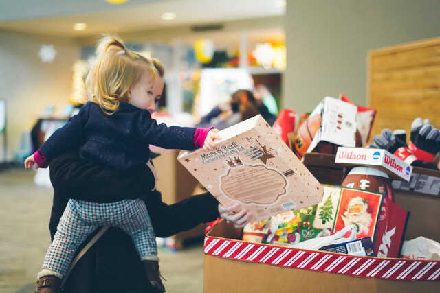 child dropping a gift into a donation box