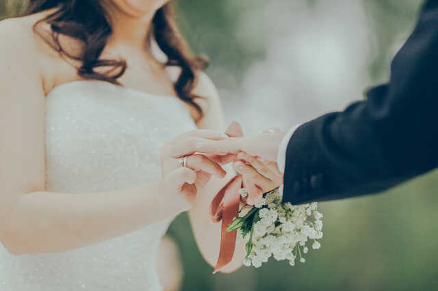 bride putting ring on husbands hand at wedding