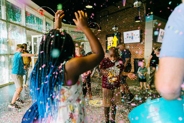 Elementary students throwing confetti in UpStreet.