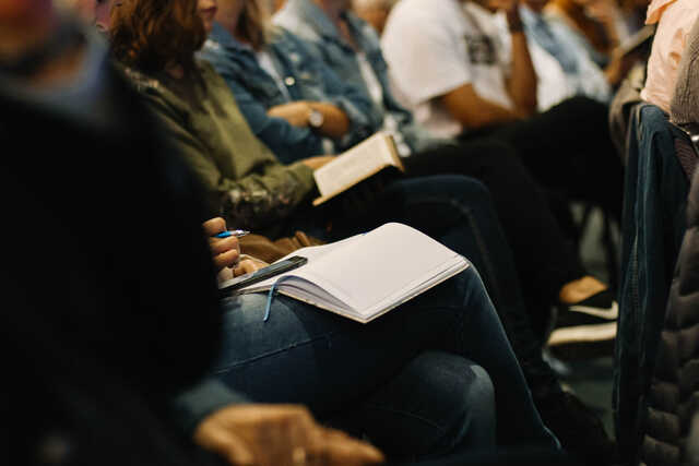 people in seats taking notes at a training seminar