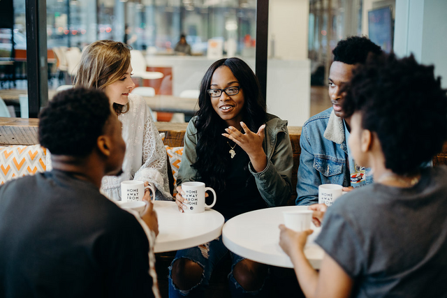 diverse group of young adults having a conversation in a coffee shop