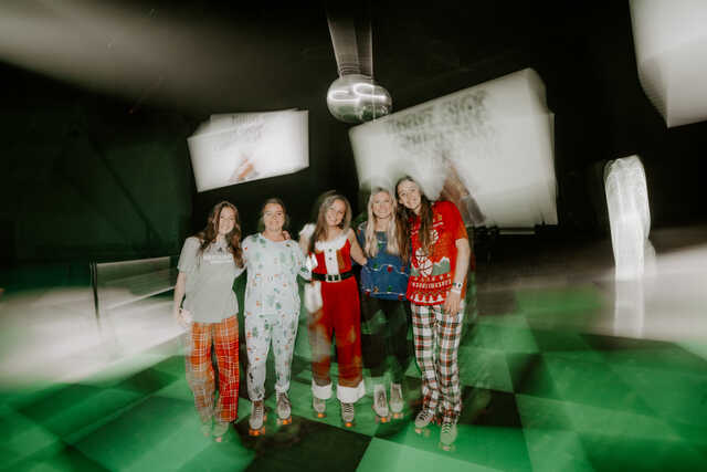 motion blur image of high schoolers in christmas pajamas roller skating under a disco ball